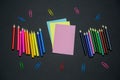 colored pencils, blank colored sheets of paper and colored paper clips on a black background copy space Royalty Free Stock Photo