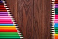 Colored pencils on brown background lying in opposite sides of wooden table Royalty Free Stock Photo