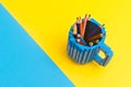 Colored pencils in a bucket on blue and yellow background. Back to scool concept