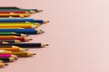 Colored pencils of different lengths are scattered, extending into the distance, on a pink background on the left side, tending to Royalty Free Stock Photo