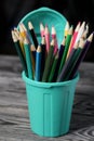 Colored pencils for drawing.  They stand in a pencil holder in the form of a trash can. On pine boards Royalty Free Stock Photo