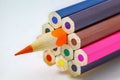 Colored pencils, ends are not sharpened, orange pencil sharpened, on white background, selective focus