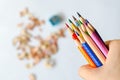 Coloured pencils in hand against blurred shavings on white backgr Royalty Free Stock Photo