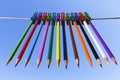Colored pencils hang on colored clothespins on a blue background Royalty Free Stock Photo