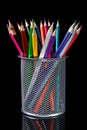 Colored pencils inside desktop silver metal mesh holder cup on black background Royalty Free Stock Photo