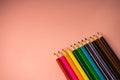 colored pencils lie on a pink background. close up, copy, spacee