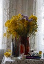 Colored pencils, markers, and paint next to a bouquet of Mimosa in a red vase on a lace tablecloth Royalty Free Stock Photo