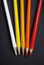 Colored pencils over black background. Warm colors. White, yellow, orange and red. Royalty Free Stock Photo