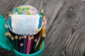 Colored pencils in a pencil holder. Nearby is a globe with a medical mask. Academic year during the epidemic