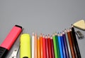 Colored pencils  pencil sharpener  eraser  markers and scissors at the bottom. Gray background. Royalty Free Stock Photo