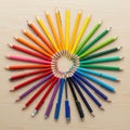 Pencils and pens arranged in a radial pattern on a light wooden Royalty Free Stock Photo
