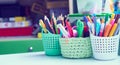 Colored pencils, pens, basket with flowers, watercolor paints and other items on wooden desk. Back to school concept. Royalty Free Stock Photo