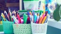 Colored pencils, pens, basket with flowers, watercolor paints and other items on wooden desk. Back to school concept. Royalty Free Stock Photo