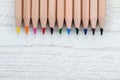 Row of colored pencils on white wooden background Royalty Free Stock Photo