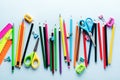 Colored pencils, scissors, notebook, ruler, pen, eraser, sharpener and more in glass. School and office stationery on light blue b Royalty Free Stock Photo