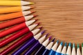 Colored pencils in a semi-circular pattern on a bamboo table. A Royalty Free Stock Photo