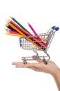 Colored pencils in shopping trolley on the palm Royalty Free Stock Photo