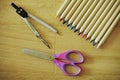 Colored pencils with colored tips arranged in a circle, open children`s purple scissors and compasses Royalty Free Stock Photo