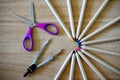 Colored pencils with colored tips arranged in a circle, open children`s purple scissors and compasses Royalty Free Stock Photo