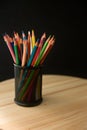 Colored pencils of various colors in a pot on a wooden table and black background with copy space Royalty Free Stock Photo