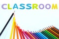 Colored pencils wave with alphabet sponge rubber of text `CLASSROOM ` over white background