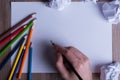 Colored pencils on white paper, man, hand, back to school concept - hand of a man preparing to write on a white sheet of paper wi