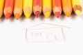 Colored pencils on a white sheet of paper on which the house is painted. Pencils red and yellow on a white Royalty Free Stock Photo