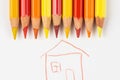 Colored pencils on a white sheet of paper on which the house is painted. Pencils red and yellow on a white background Royalty Free Stock Photo