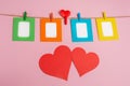 Colored photo frames are attached to the rope with clothespins. Pink background decorated with red hearts. Valentine`s Day Royalty Free Stock Photo