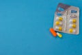 Colored pills, tablets and capsules on a blue background.