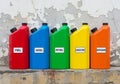 Colored plastic fuel containers are lined up against a weathered, Royalty Free Stock Photo