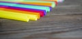 Colored plastic straws lie on a wooden table in a row. A row of colored cocktail straws. wooden background and plastic Royalty Free Stock Photo