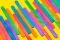 Colored popsicle sticks arranged side by side. Wooden ice cream sticks on yellow paper. Multicolored background Royalty Free Stock Photo