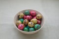 Colored quail eggs in a bowl on fabric background