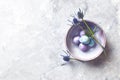 Colored quail eggs and sea holly flowers in a ceramic bowl flat lay arrangement