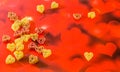 Colored (red, yellow an orange) heart shape pasta, colored degradee bokeh background, close up Royalty Free Stock Photo