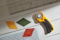 Colored rhombuses, rotary cutter, ruler and cutting mat on a white wooden surface