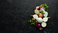 Colored ripe onions on wooden board on black background.