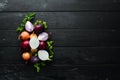 Colored ripe onions on wooden board on black background.