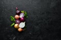 Colored ripe onions on wooden board on black background.