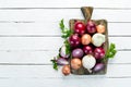 Colored ripe onions on wooden board on white wooden background. Top view