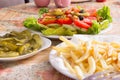 Colored salad and frensh fries with Pickled Cucumber on white plates