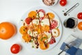 Colored salad with sliced red yellow tomatoes, mozzarella, olive oil, pepper and salt on white background. Vegan food