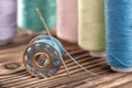 Colored sewing thread and bobbin on a wooden background