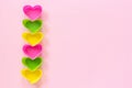 Colored silicone heart shaped molds dish for baking cupcakes lined in row left edge on pink paper background. Template for