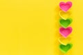 Colored silicone heart shaped molds dish for baking cupcakes lined in row right side on yellow paper background. Template for