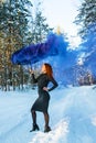 Colored smoke. Girl in black dress under a black umbrella from which blue smoke streams