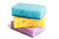 Colored sponges for washing dishes and other domestic needs. Yellow sponge lies between the blue and purple sponges at a slight