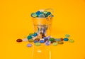 colored stones in glass in jar in bucket on orange background Royalty Free Stock Photo