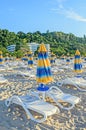 Colored stripped sun umbrellas, beach sand and beds